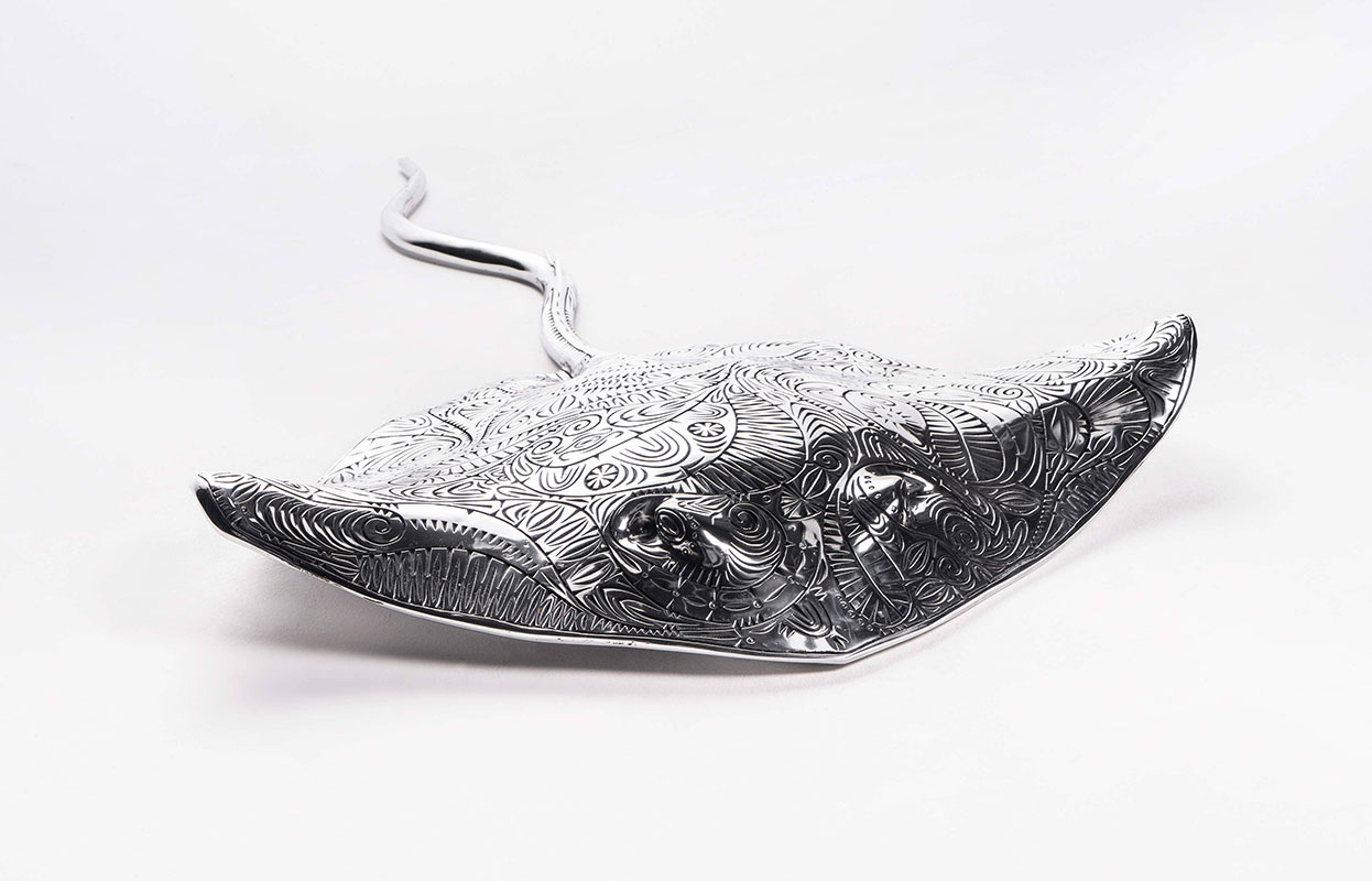 Artwork representing a stingray made from aluminium with incised decoration. - click to view larger image