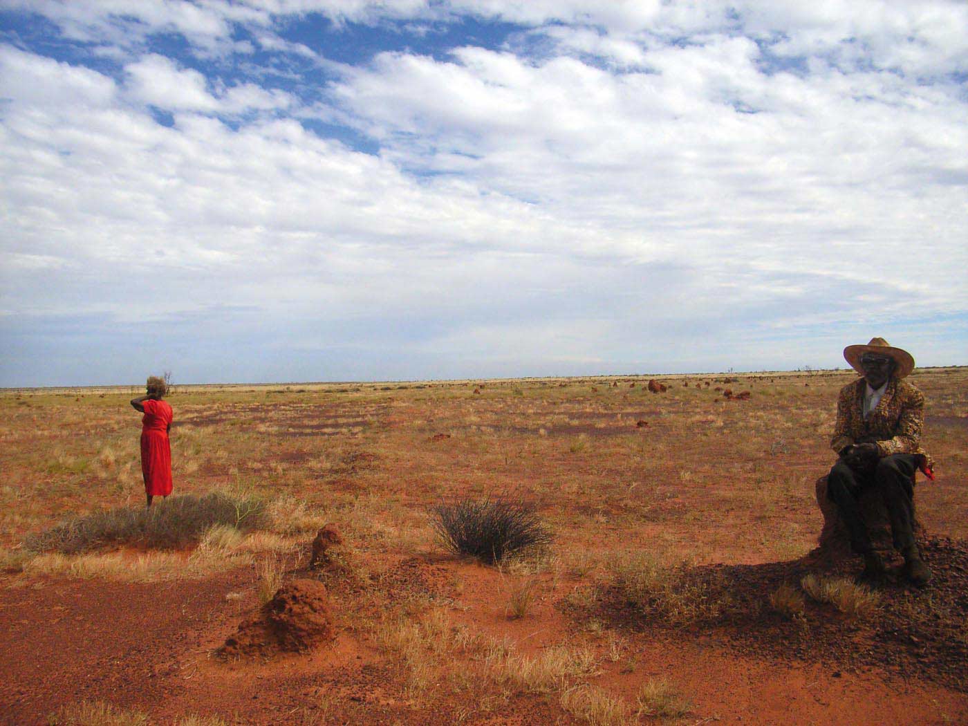 Colour photo of woman and man in a barren looking landscape.