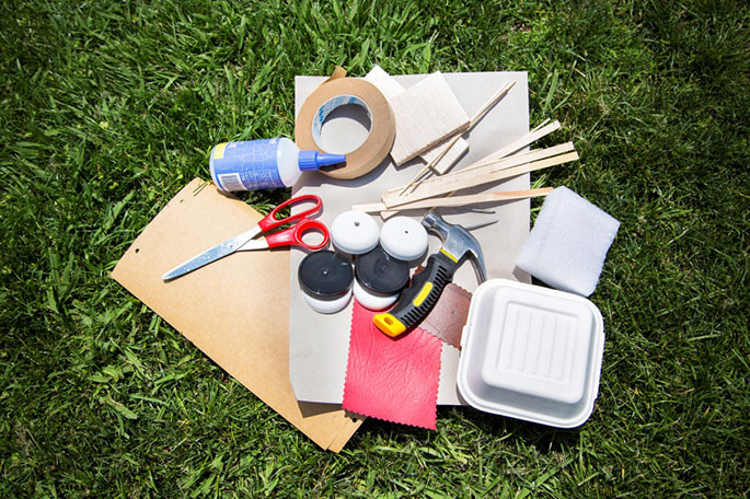 Materials needed for making a toy horsedrawn cart including: scissors, tape, glue, skewers, sticks and a foam box.