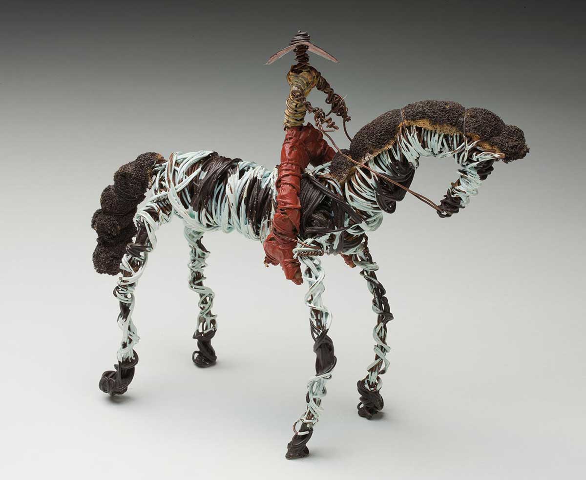 Bush toy consisting of a figure on a black and white horse made from painted coiled wire and fabric. - click to view larger image