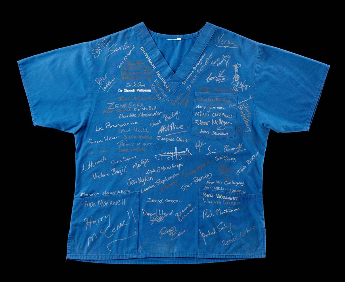 A blue scrub with pockets featuring multiple signatures across the front.