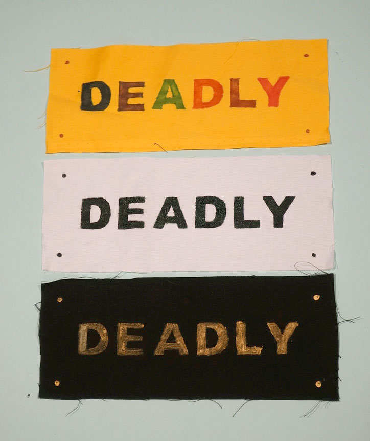 Three pieces of fabric with the word Deadly printed and painted on each in different colours.