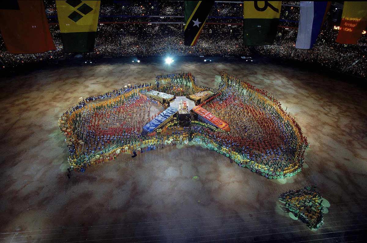 Hundreds of performers use their bodies to create a multi-coloured map of Australia in the centre of a stadium.