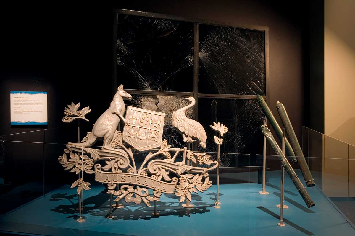 Bomb damaged Australian coat of arms displayed alongside other damaged objects.  - click to view larger image