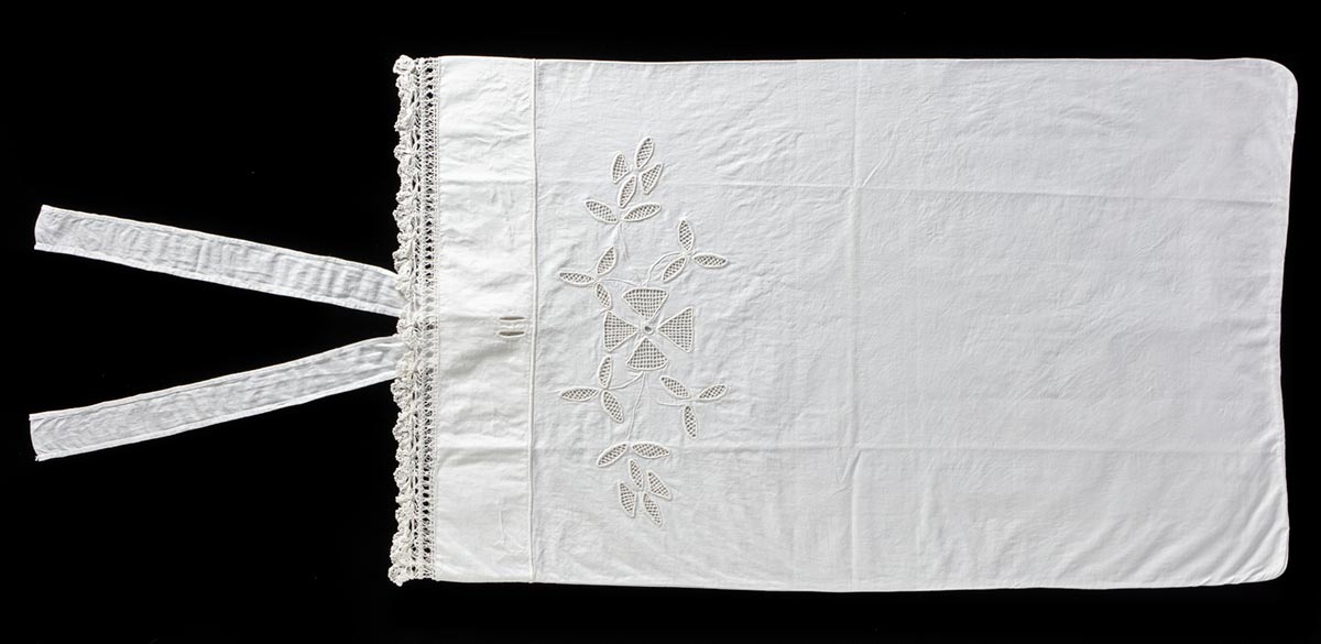 Rectangular white woven pillowcase, with crocheted detailing on the left edge and two thin eyelets with a tie closure. The pillowcase is decorated with an embroidered floral pattern, with one large four-petal flower in the centre, surrounded by smaller three-petal flowers. - click to view larger image
