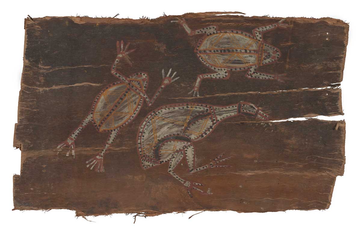 A bark painting worked with ochres on bark. It depicts two frogs and a bird, each painted in white with dotted outlines and yellow zigzags on the body. The painting has a natural brown background. - click to view larger image