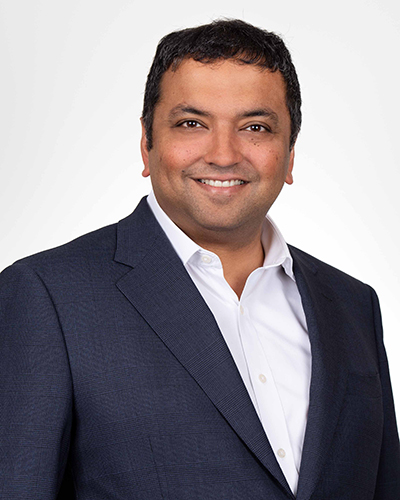 A photograph of Amit Singh. Amit wears a blue suit jack and white shirt. 