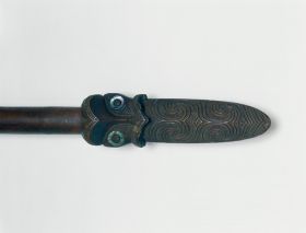 Club made of heavy brown wood, the grip end decorated with line and facial ornaments, the eyes inlaid with mother-of -pearl shell.