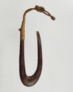 Fishhook made of a finely polished piece of hardwood. The point of the hook is flat on the side and the upper end of the shank is supported and secured with plaited coconut fibres.
