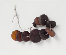 Jewellery & Adornment made from reddish-brown and blackish-brown tortoise shell discs arranged on a string.