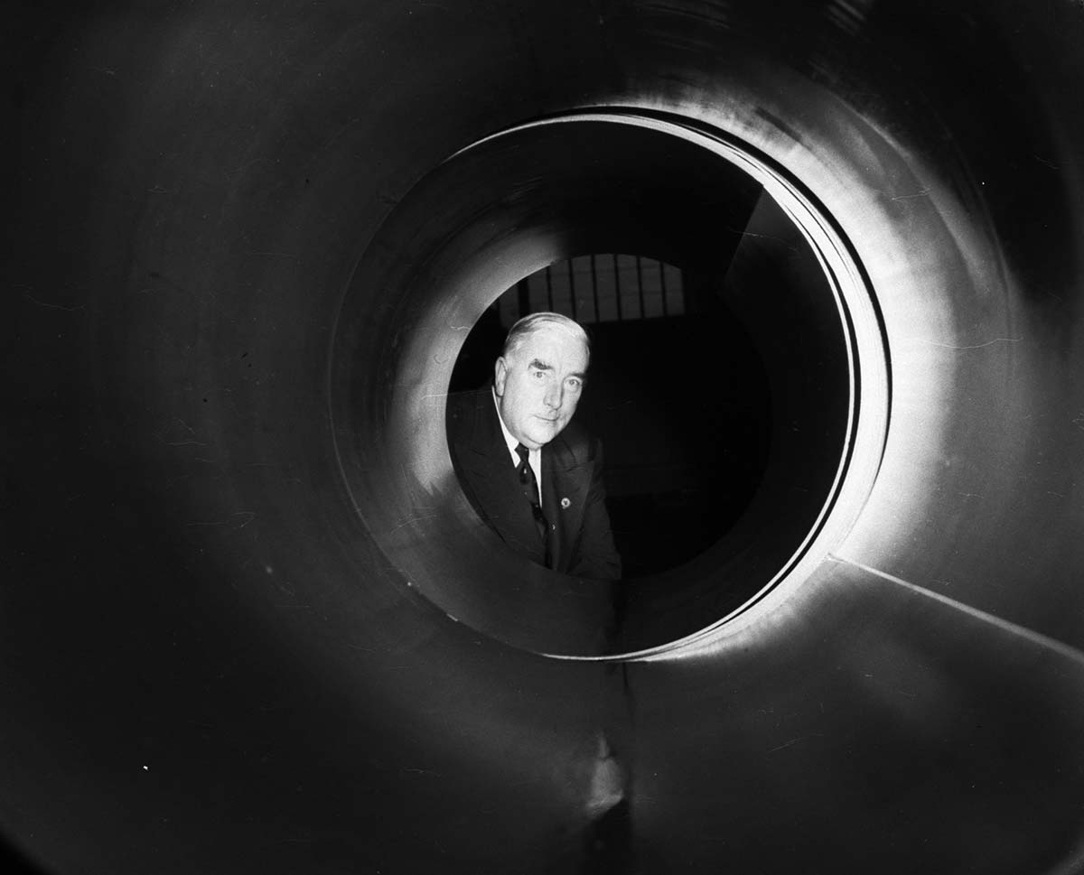 A black and white photo of an older man looking through a tunnel.