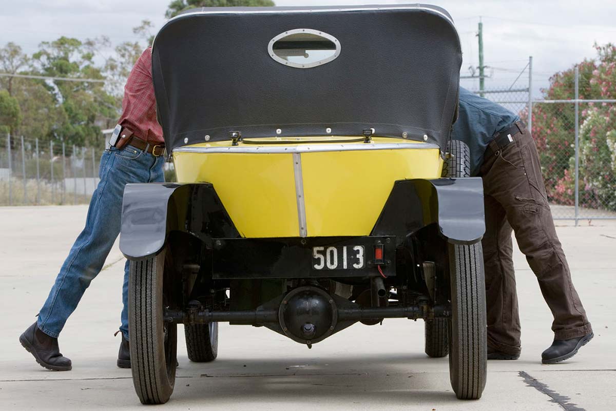 Rear view of Citroen car, showing conservators leaning into front, on either side.
