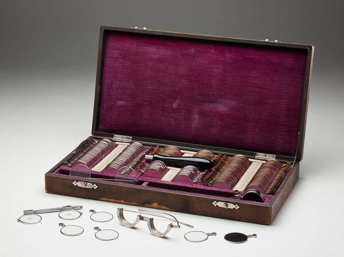 Various lenses and frames stored in a rectangular brown leather case with purple velvet lining. - click to view larger image