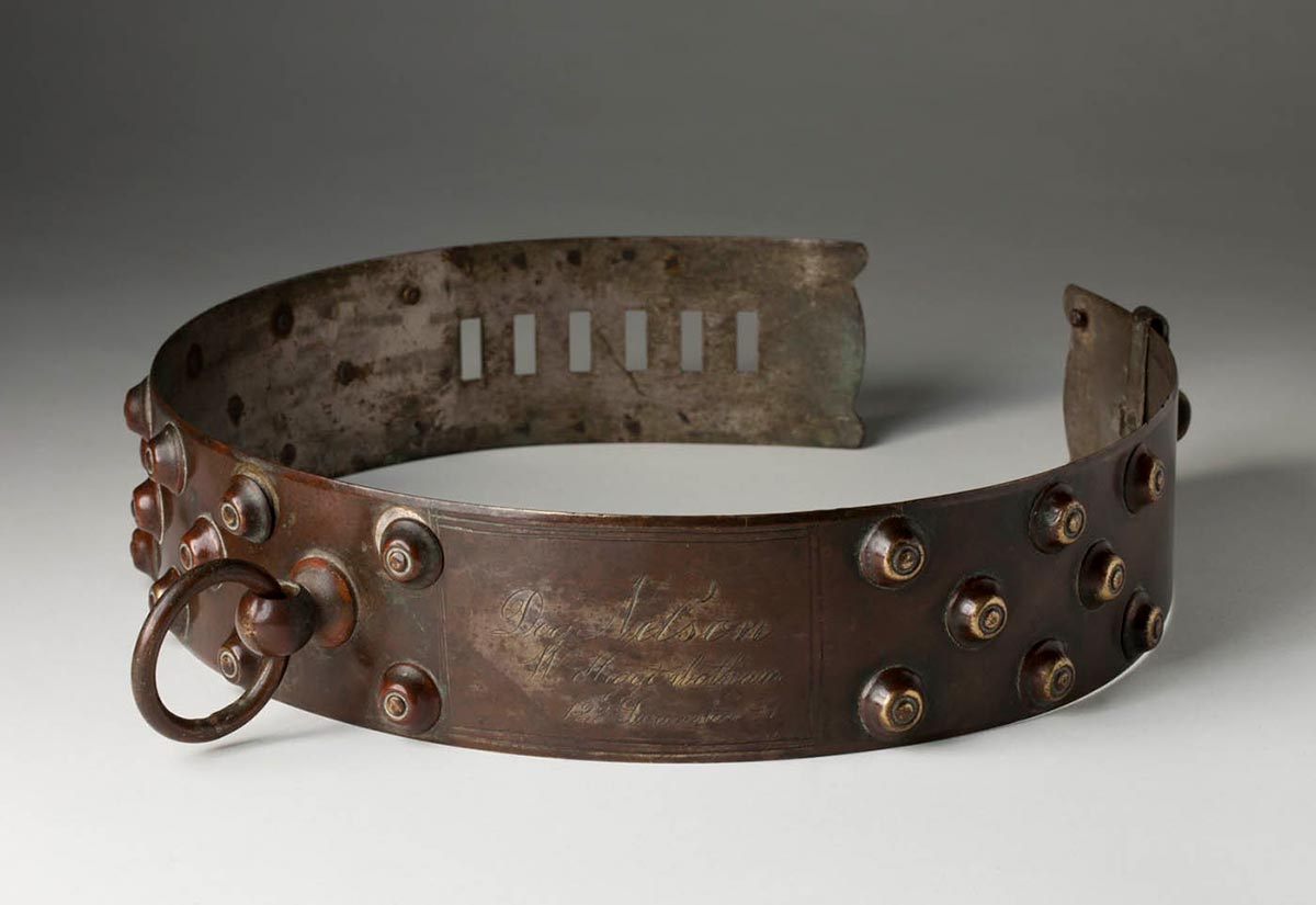 Copper patinated circular collar with raised studs on the outside and a small ring attached at the seam.
