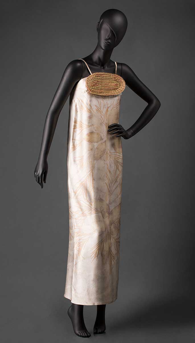 Front view of a mannequin wearing silk dress that is beige in colour with pale brown and yellow leaf designs throughout it. - click to view larger image