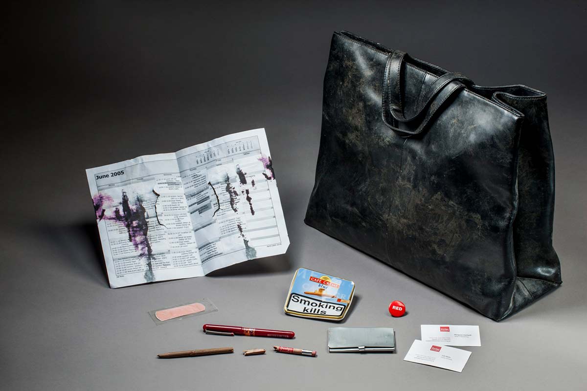 A black leather briefcase with attached stitched handles holding a number of small objects. - click to view larger image
