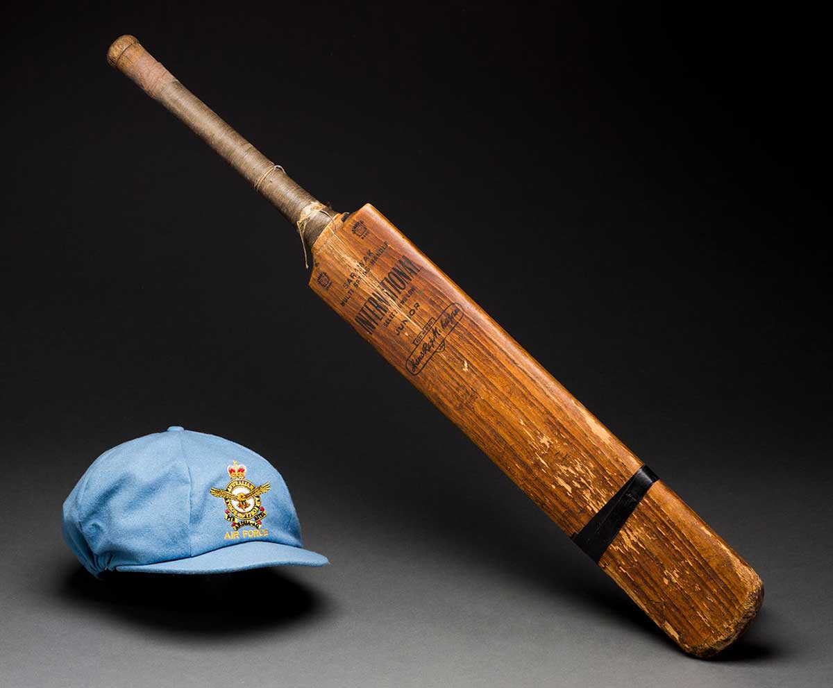 A blue cricket cap and a wooden cricket bat. - click to view larger image