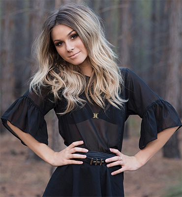 A portrait photo of a woman standing with her hands on her hips.