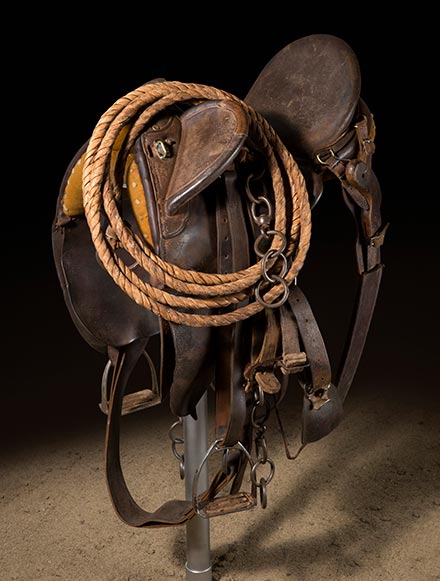 A dark brown leather saddle mounted on a pole. - click to view larger image