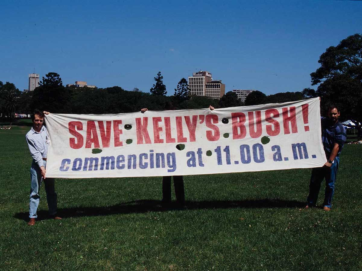 Two men holding up a protest banner that reads 'Save Kelly's Bush! commencing at 11:00am.' - click to view larger image