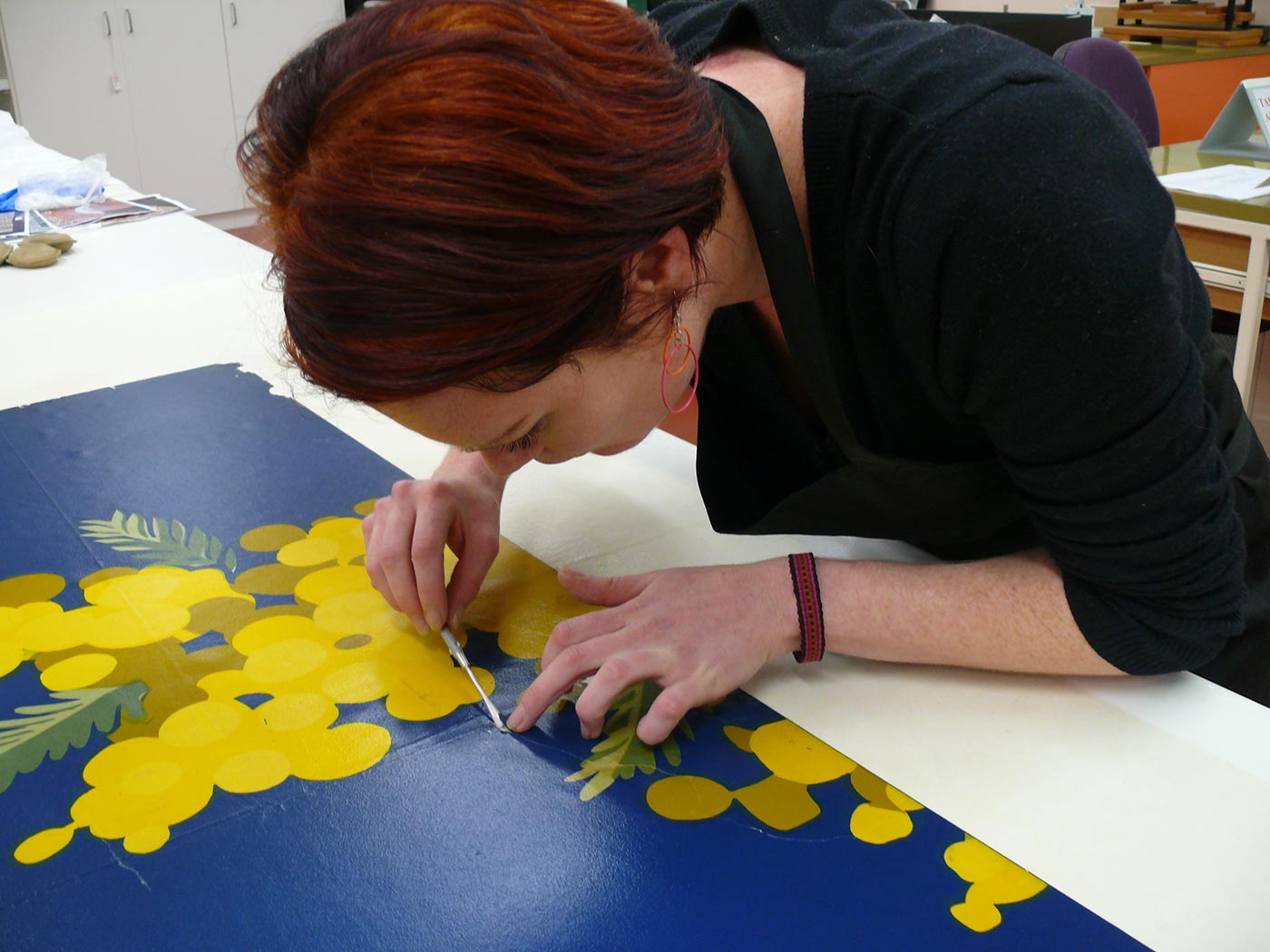 A museum conservator replacing a loose fragment of a Holden billboard poster. - click to view larger image