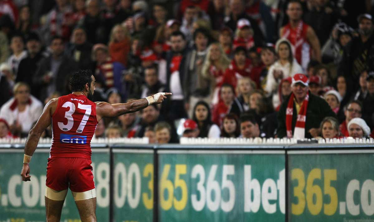 Colour photo of Adam Goodes on the field pointing towards the crowd of spectators.