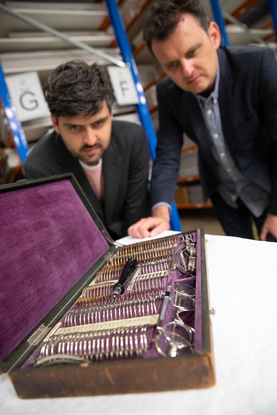 Slava and Leonard Grigoryan inspect a velvet-lined wooden case containing various optical tools. - click to view larger image