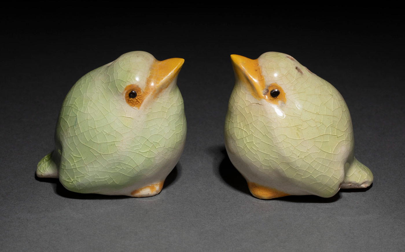 A pair of baby kookaburra salt and pepper shakers. They are a green in colour with yellow beaks.