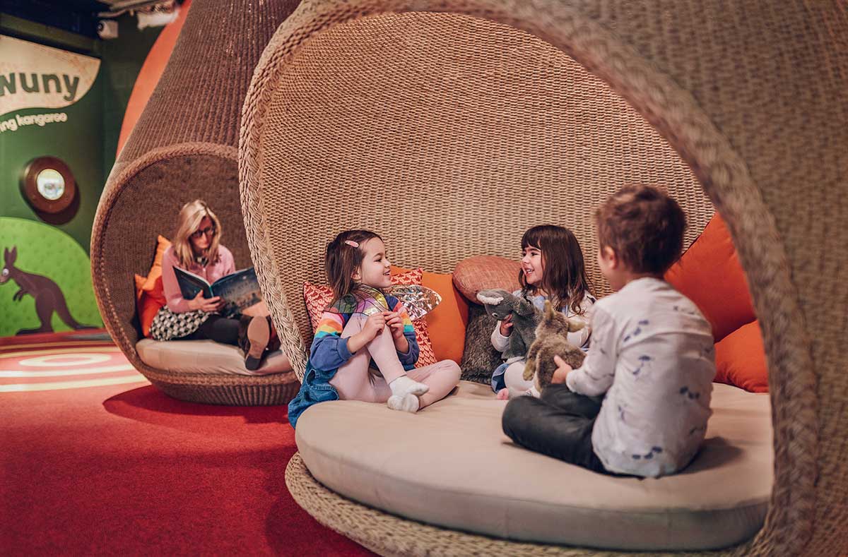 Three children sit and talk in a large cushioned pod 