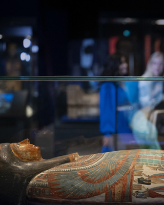 An Egyptian coffin lies in a glass case.