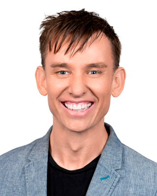 Photograph of Wayne Herbert. Wayne is smiling at the camera, he has brown hair and large smile.