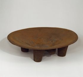 Kava bowl made of one piece of wood that is round and shallow, and rests on four legs.