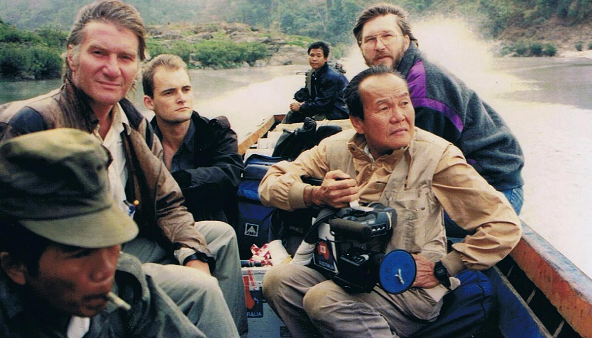 A group of men in a boat. One is holding a camera.