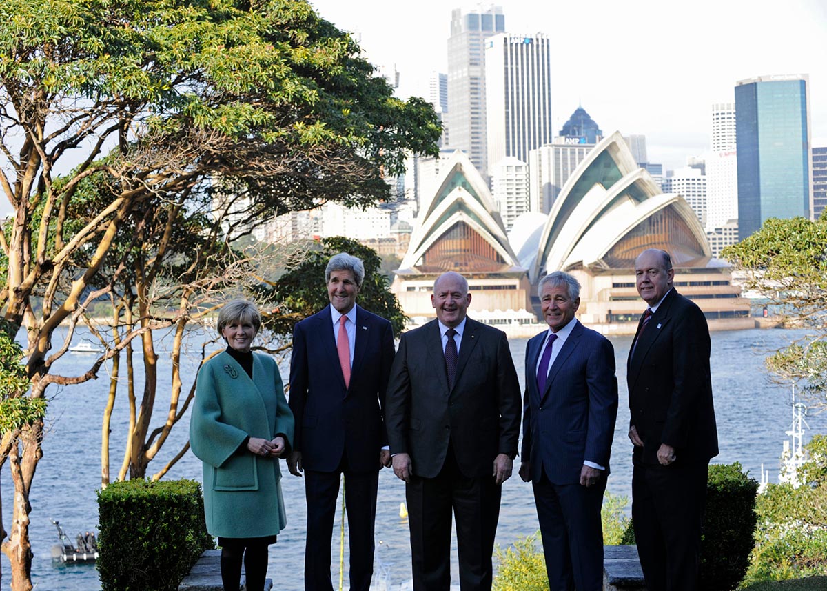 The five people mentioned in the caption pose in the garden of Admiralty House with Sydney Harbour and the Opera House in the background.
