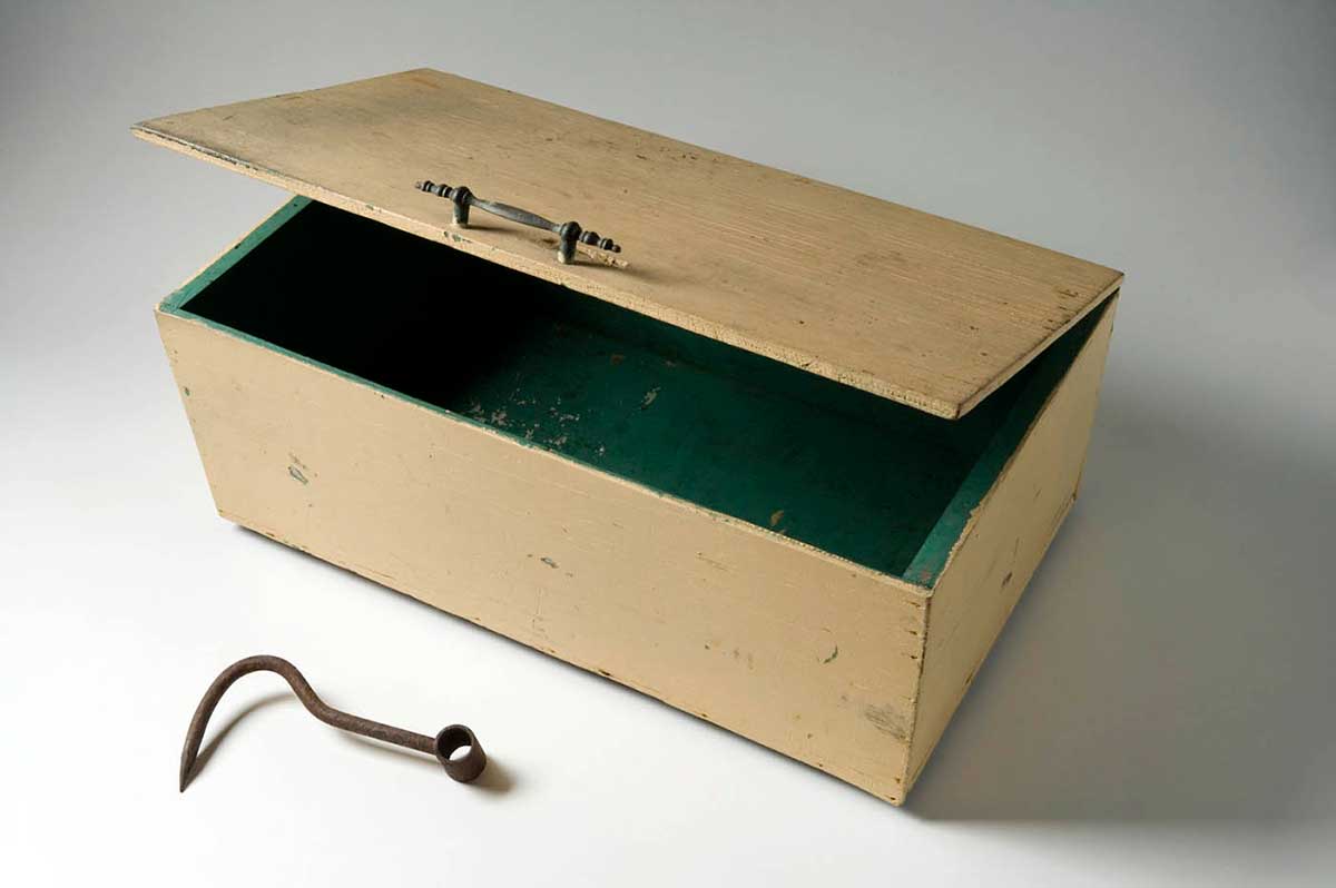 A rectangular yellow tuckerbox box painted green inside and a rusted hook.