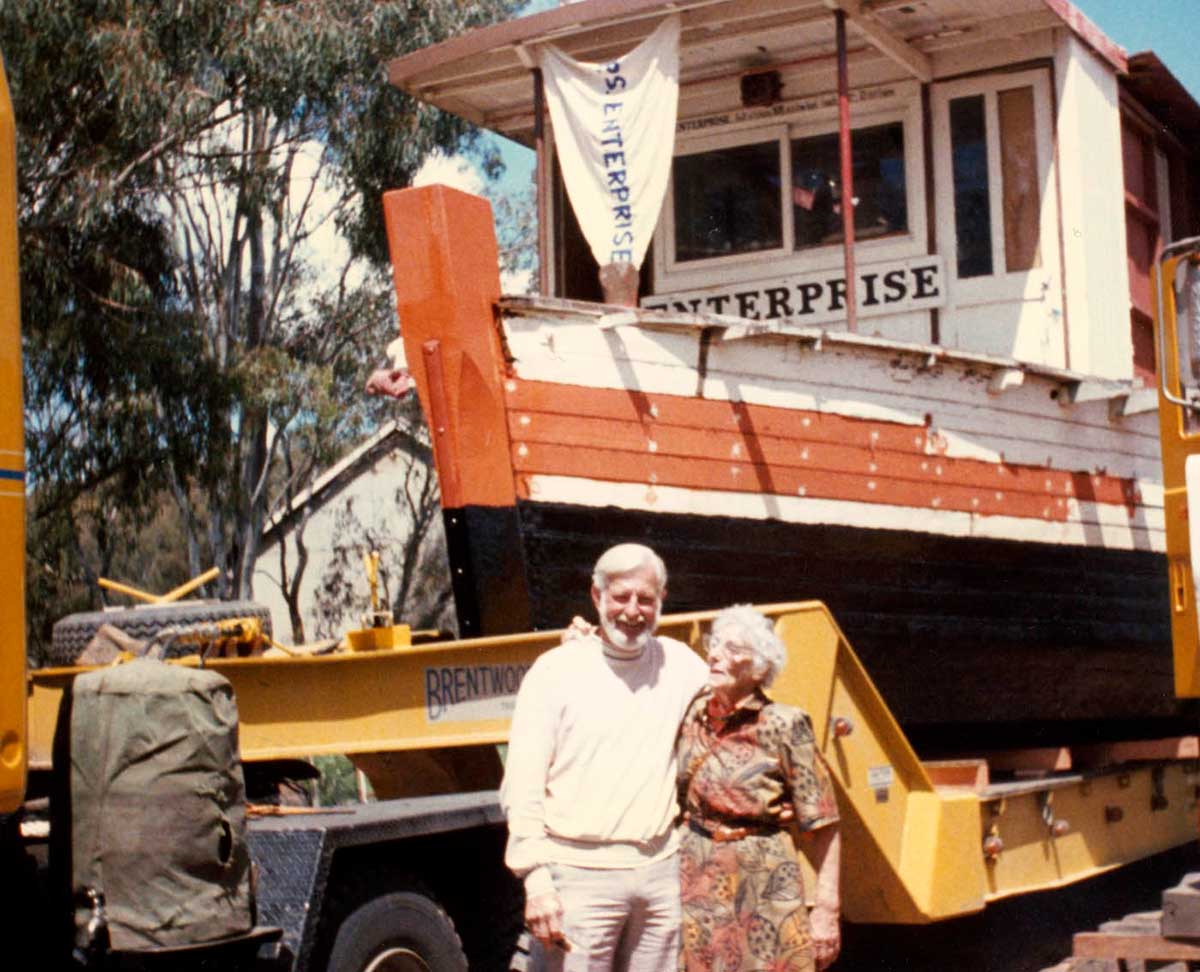A colour photograph of John Robinson and his sister with the PS Enterprise in the background. - click to view larger image