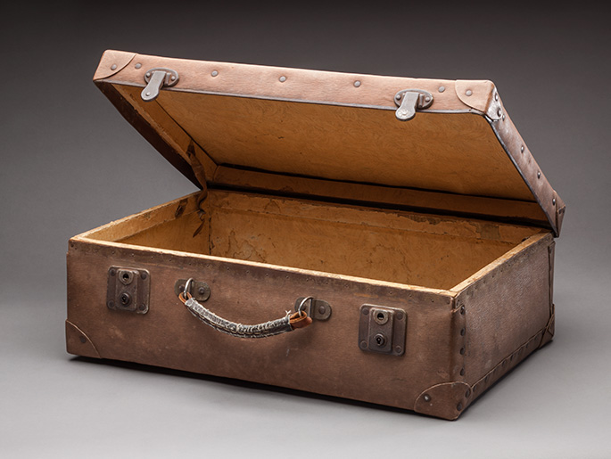 An open suitcase with metal clasps at the front, a worn handle and reinforced corners.