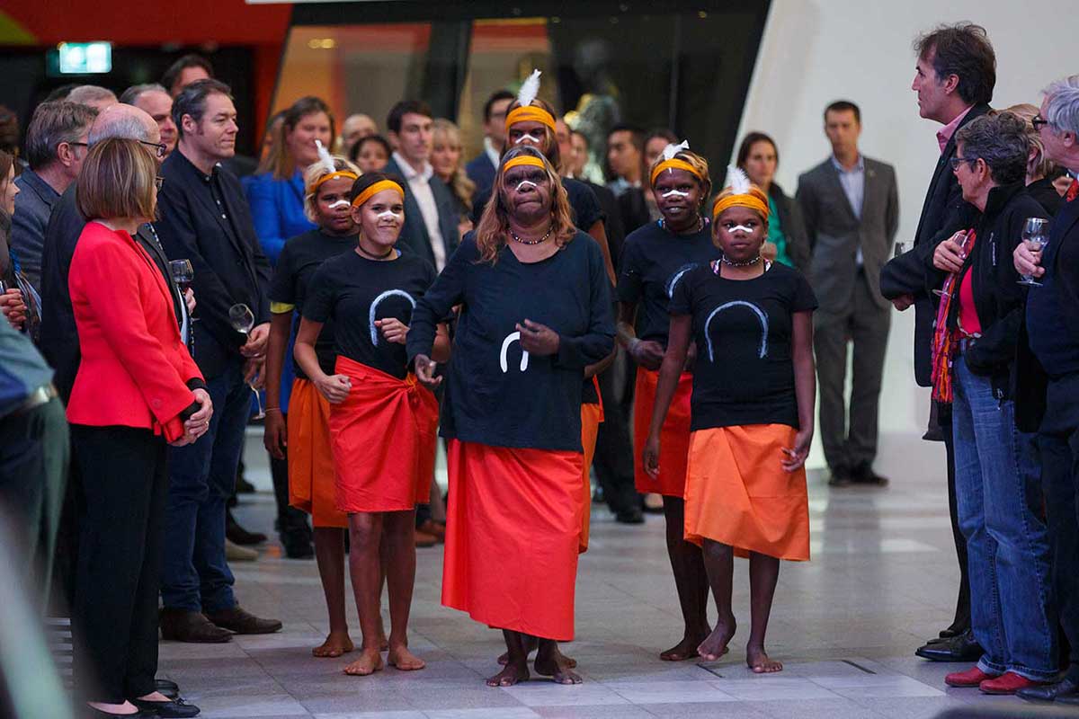 Audience watching a performance by a small group of women in traditional costume - click to view larger image
