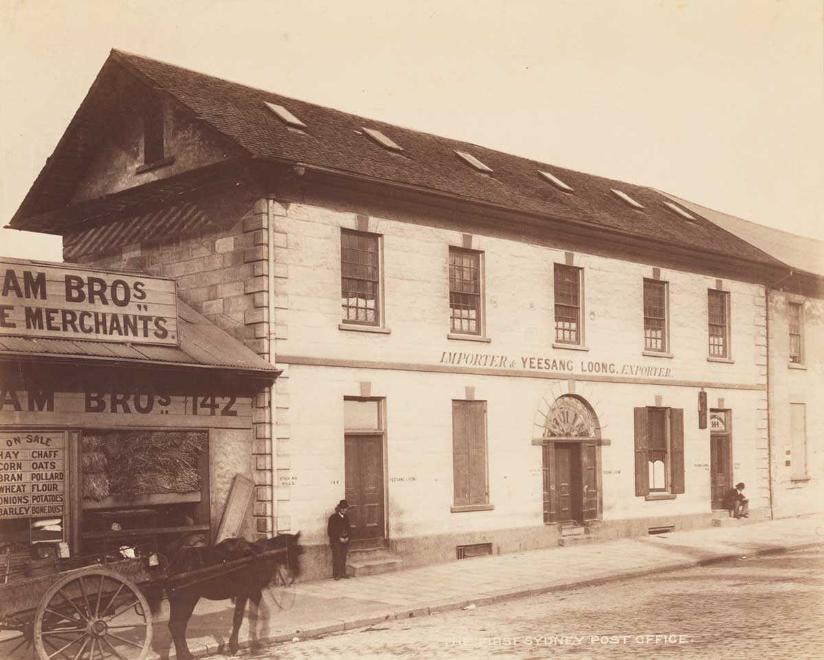 Photo of simple two-storey building with two men and a horse and cart out the front.
