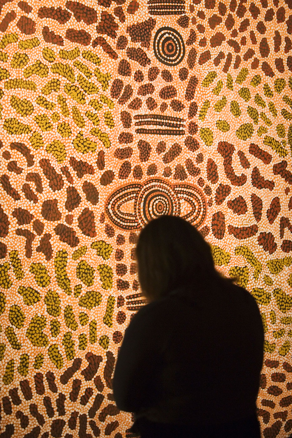 Rear silhouette of visitor looking at dot painting. - click to view larger image