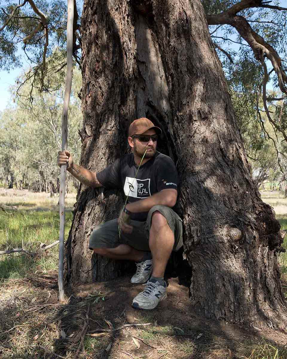 A man rests at the base of a large tree. - click to view larger image