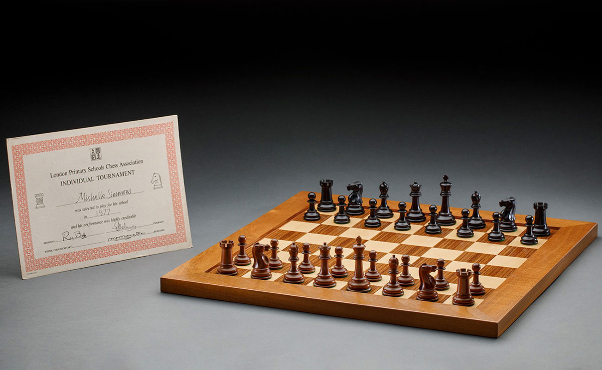 A certificate and a chess set including a wooden board and 32 wooden chess pieces. 