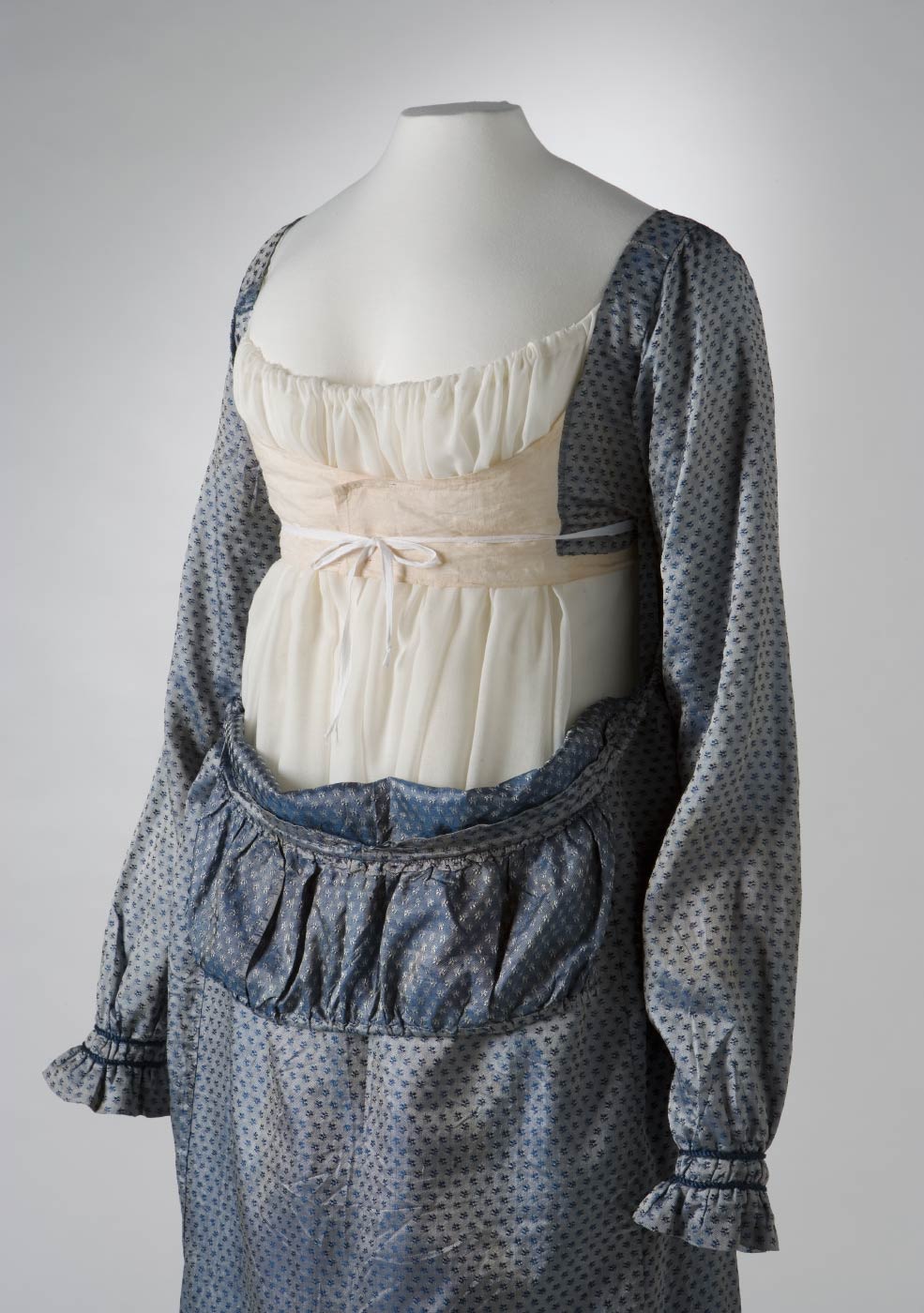 Front view of a blue silk full length empire-line dress with the bib-front down and the bodice revealed. - click to view larger image
