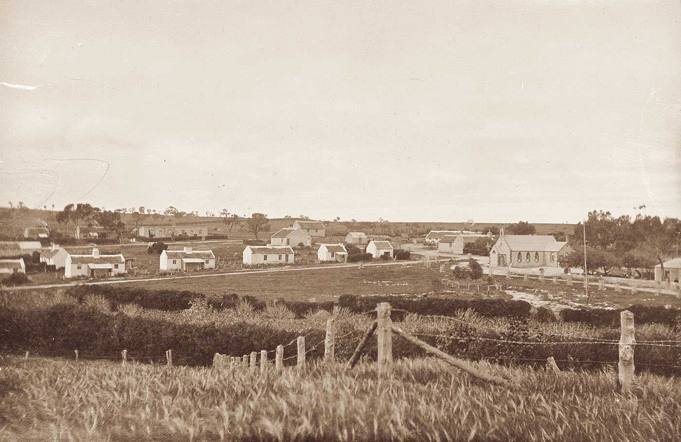 Black and white photo of rural landscape with homesteads in the distance.