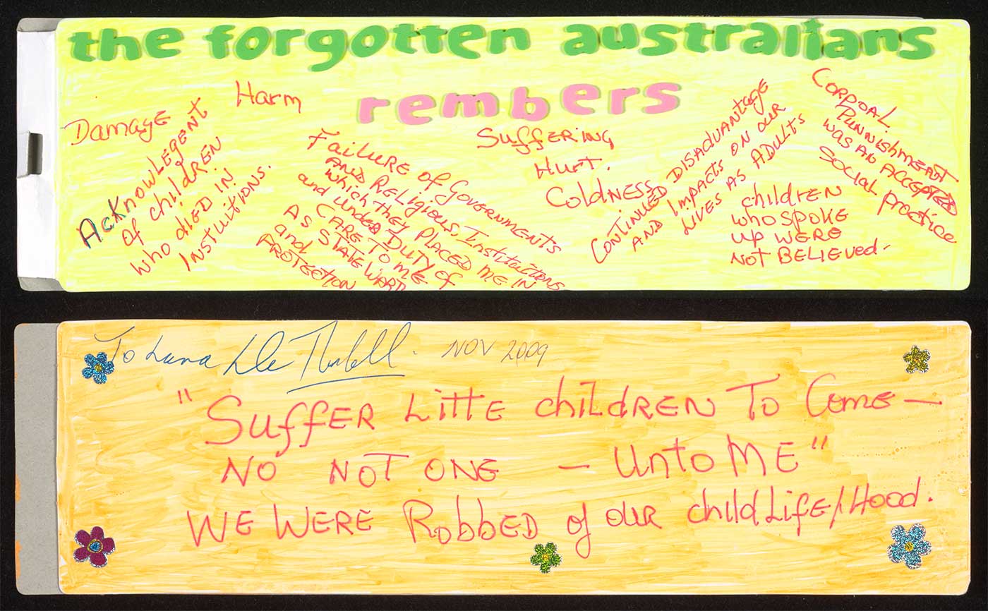 A photograph of a small rectangular cardboard sign coloured flourescent yellow on both sides. Raised green letters on the front read: 'the forgotten australians' with 'rembers' in pink. Handwritten text in red pen includes 'Acknowlegent of children who died in institutions', 'Failure of Governments and Religious Institutions which they placed me in and under duty of care to me as a state ward and protection'. The reverse is signed 'To Lana M Turnbull' above red handwriting that reads 'Suffer Litte children to Come - NO NOT ONE - unto ME. We were Robbed of our child life/hood'. - click to view larger image