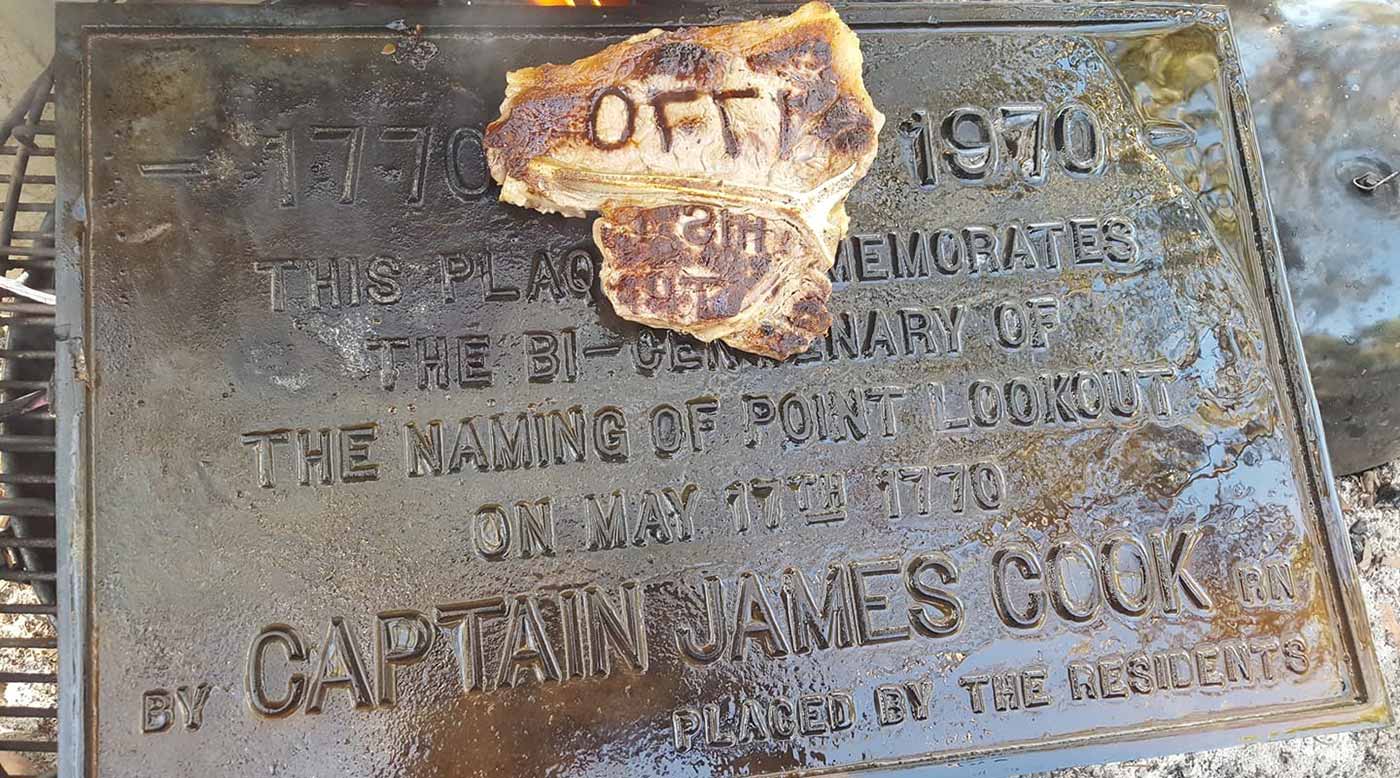 Colour photograph of a plaque attributed to Captain James Cook with a steak with text seared into the surface sitting on top.