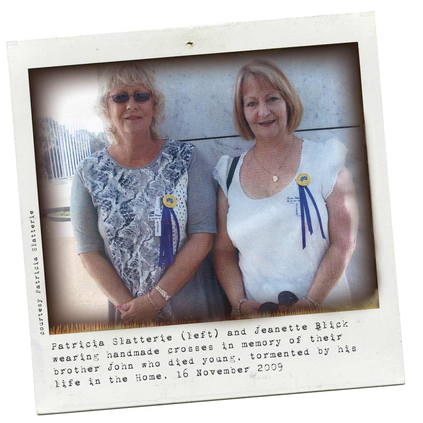 A colour Polaroid image of two women wearing badges and blue ribbons pinned to their shirts. Typewritten text below reads 'Patricia Slatterie (left) and Jeanette Blick wearing handmade crosses in memory of their brother John who died young, tormented by his life in the Home, 16 November 2009.' 'Courtesy Patricia Slatterie' is typed along the left side. - click to view larger image