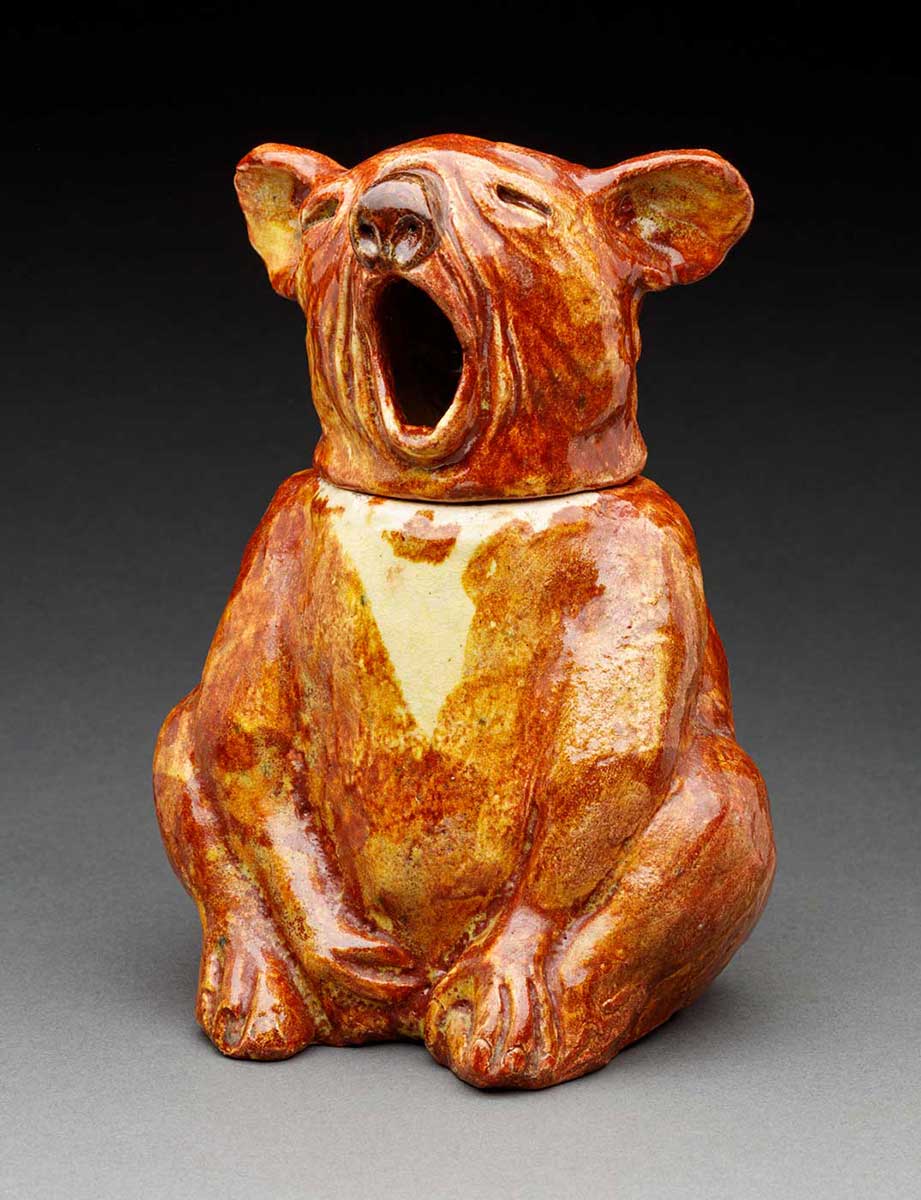A ceramic biscuit jar in the shape of a yawning koala. It is painted in shades of brown and cream. - click to view larger image