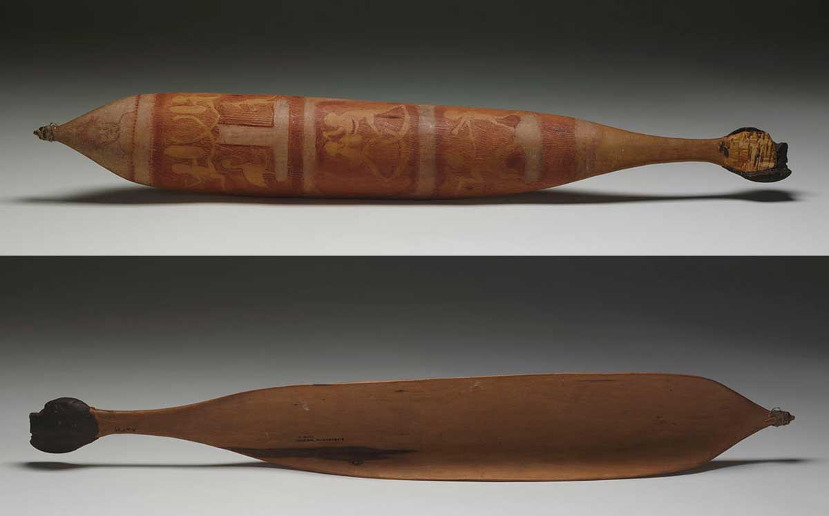 Front and back views of a wooden spear-thrower, laying on its side. The back view shows Aboriginal customary patterns and designs on the surface. The front view shows the unmarked inside of the spear thrower. Natural resin covers the handle at one end while the spear-retaining hook can be seen at the other end. - click to view larger image