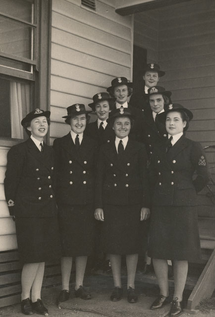Black and white photograph of a group of women in military uniform, standing in the entrance of a weatherboard building. - click to view larger image